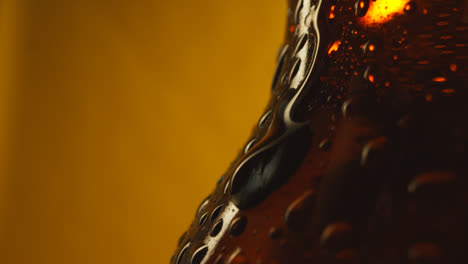 Macro-Shot-Of-Condensation-Droplets-Running-Down-Bottle-Of-Cold-Beer-Or-Soft-Drinks-Against-Yellow-Background